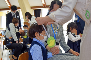 写真：年長組からのプレゼントを受け取る新入園生