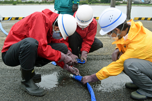 写真：排水用ポンプのホースを接続している様子