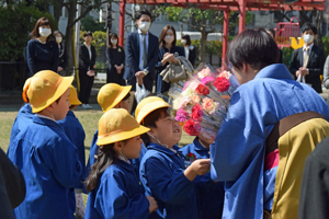 写真：先生に花を渡す園児たち