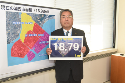 新しい浦安市の面積が18.79平方キロメートルであると書かれたフリップを持つ市長