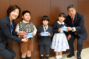 写真：読書通帳を受け取った新小学校1年生3人と市長、教育長