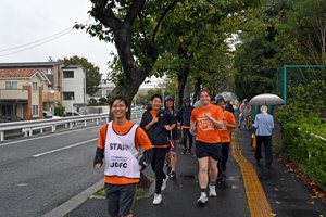 写真：オレンジ色のTシャツを着て道を走る参加者