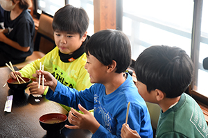 写真:みそ汁を食べる児童たち