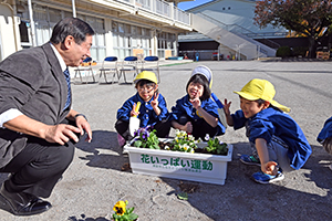 写真：植え終わったプランターの前で笑顔の園児たち