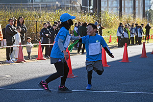 写真：小学生男子・女子の部でたすきをつなぐ様子